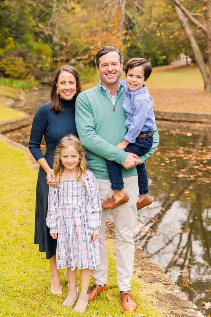 Family standing in a Buckhead Atlanta GA park near a pond during fall family mini session with family photographer Laure Photography