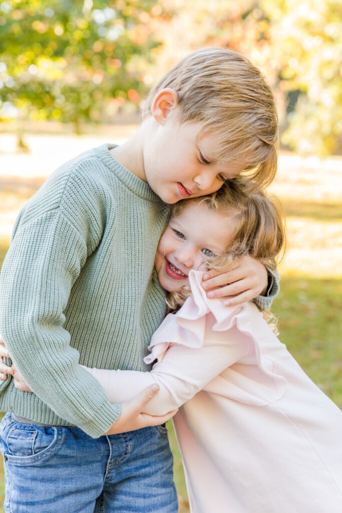 siblings hugging during fall mini session in Atlanta park by family photographer Laure photography