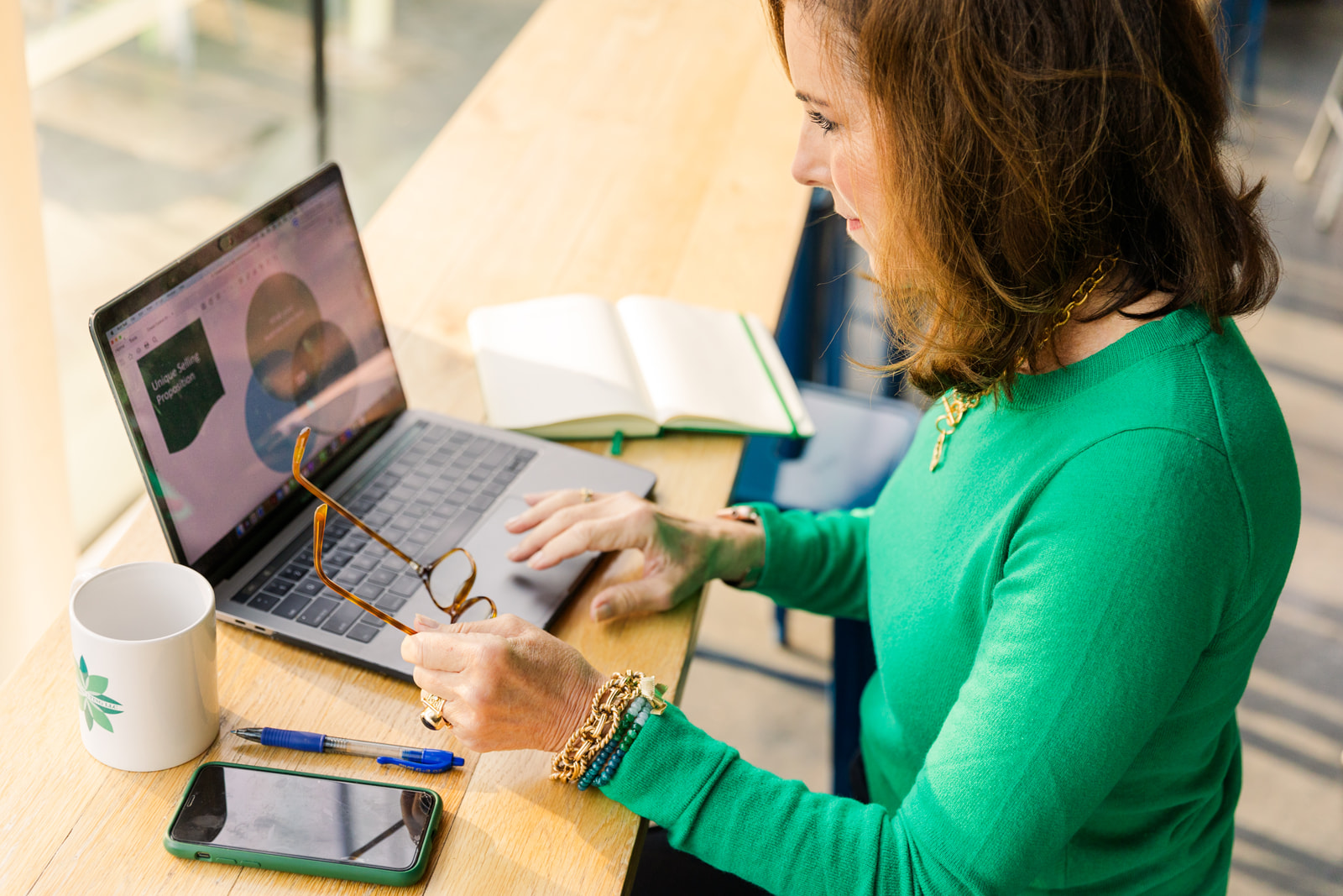 woman working on a presentation on her laptop in a coffee shop during brand photo shoot Atlanta with Laure Photography