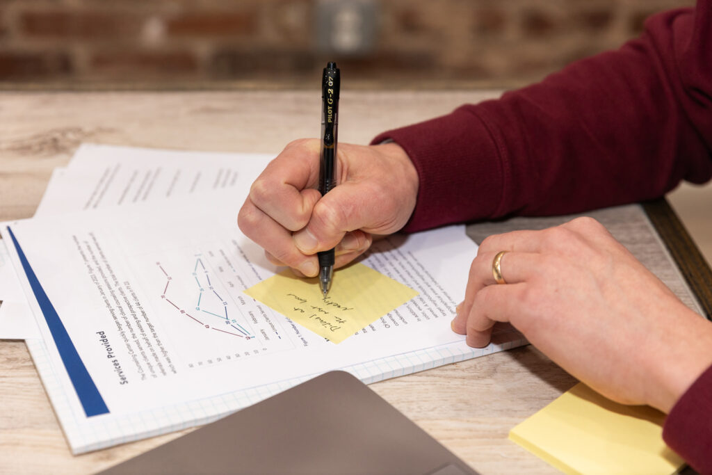 Close-up of hand writing note on post-it over business documents during brand photoshoot in Atlanta
