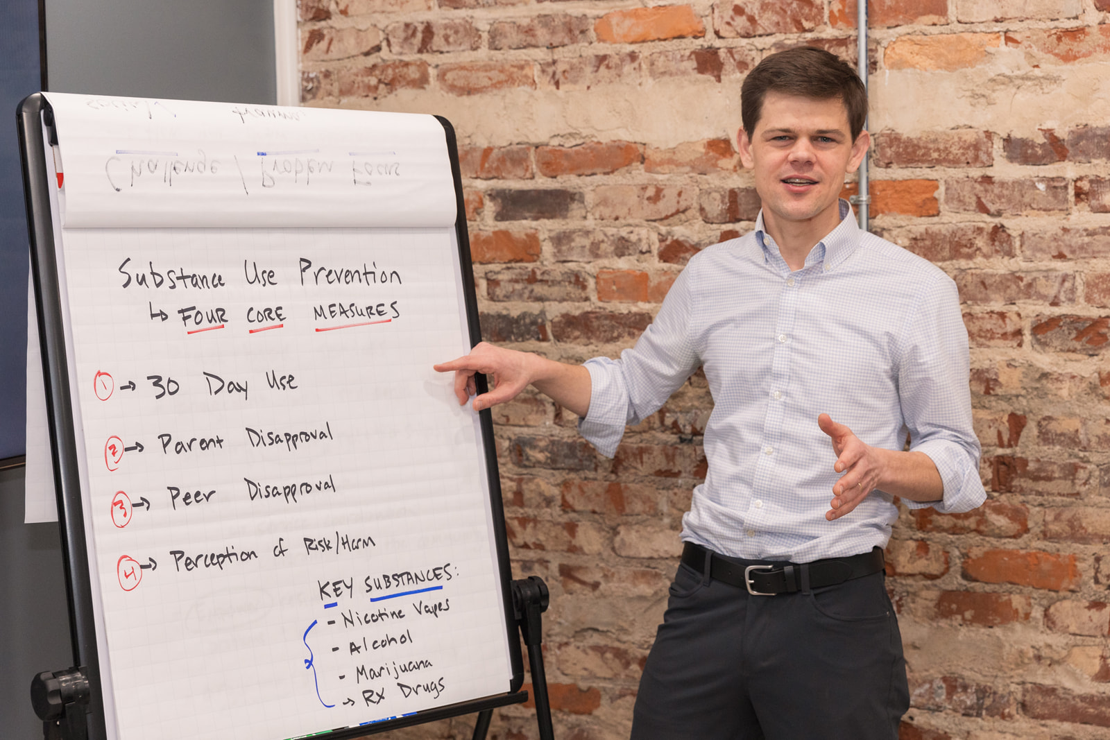 Business casual consultant pointing to tripod paper board during client meeting in Atlanta