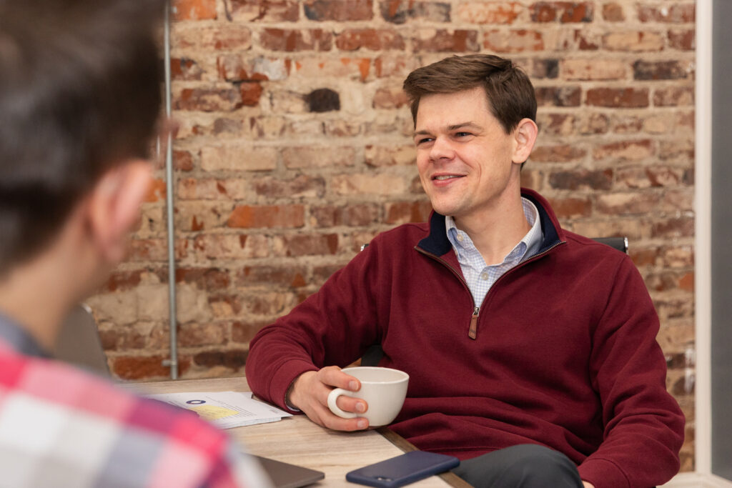 Consultant holding coffee and attentively listening during business meeting in conference room in Atlanta
