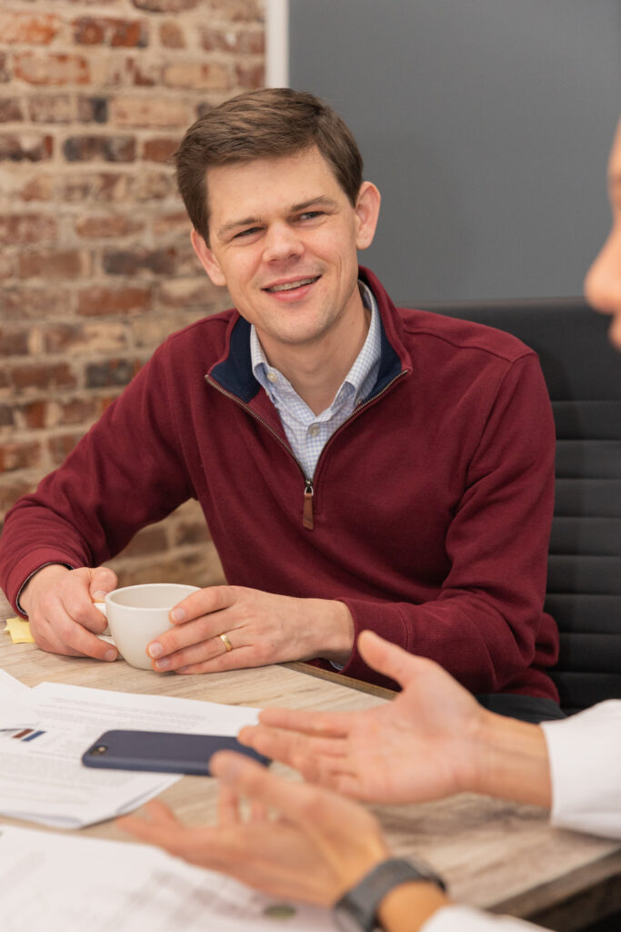 Consultant holding coffee and listening to client during business meeting in Atlanta conference room