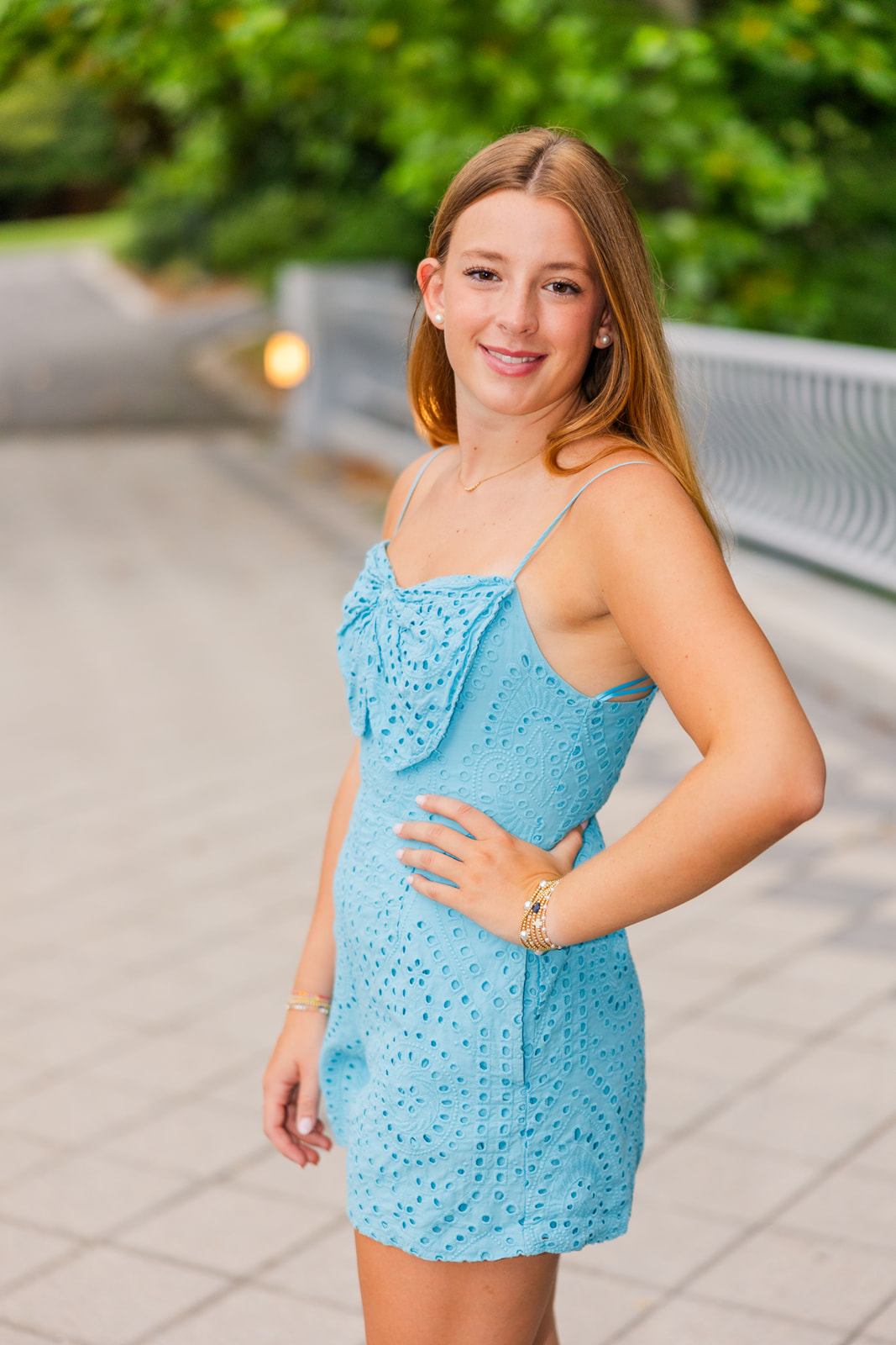 teenager standing on a bridge wearing a light blue romper her hand on her hip during senior photo session in Atlanta GA park