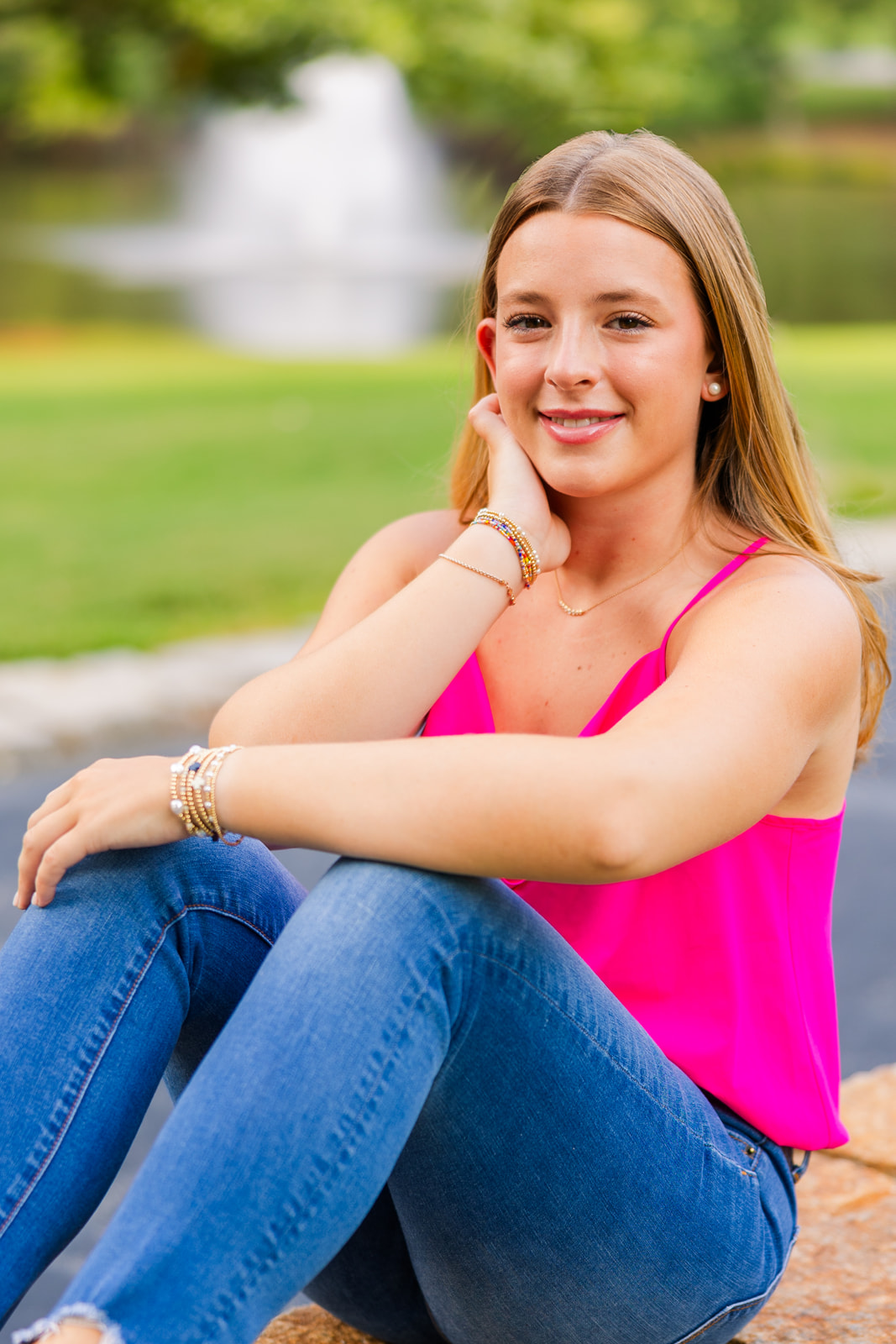 teenager sitting on the ground in front of a fountain in an Atlanta GA park during professional portraits