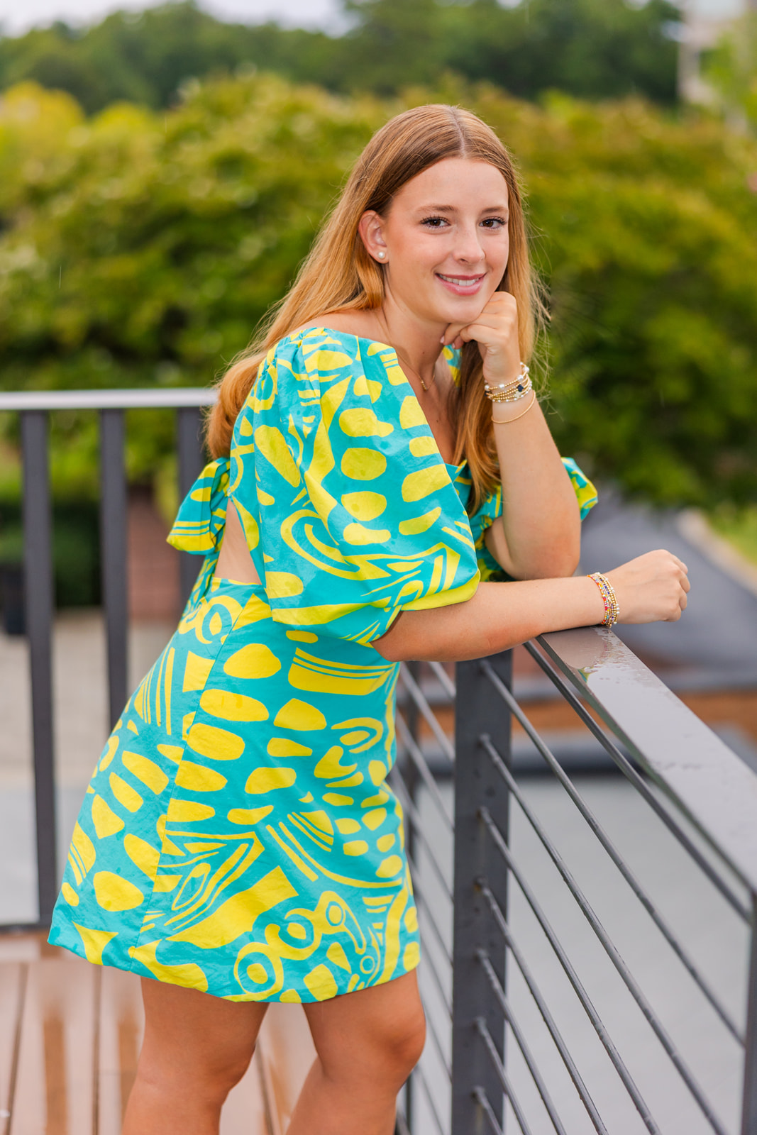 senior girl leaning on a ramp wearing colorful blue short dress with yellow patterns in Lenox Park GA during Senior portrait photo session