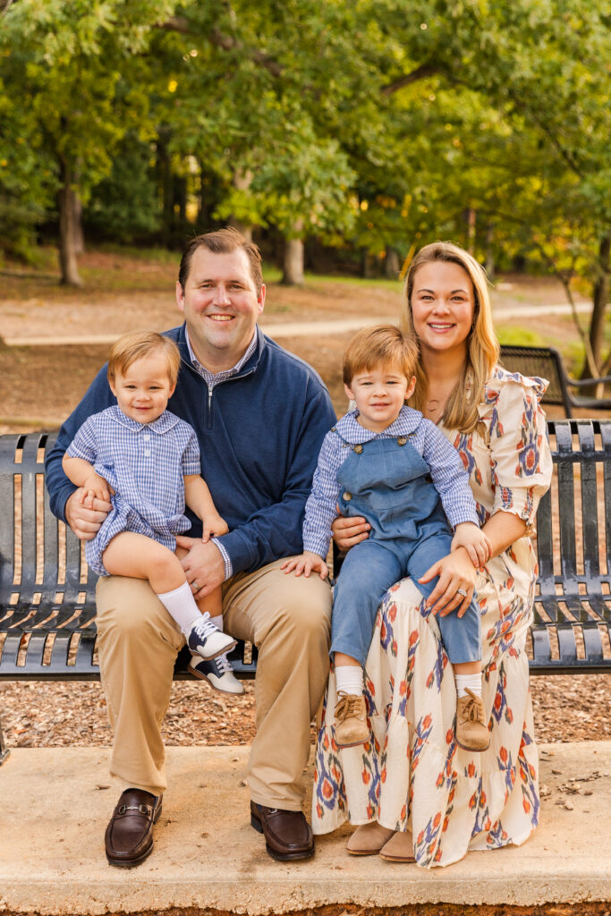 Parents with toddler boy and young boy sitting on a Brookhaven Atlanta park bench by Laure Photography