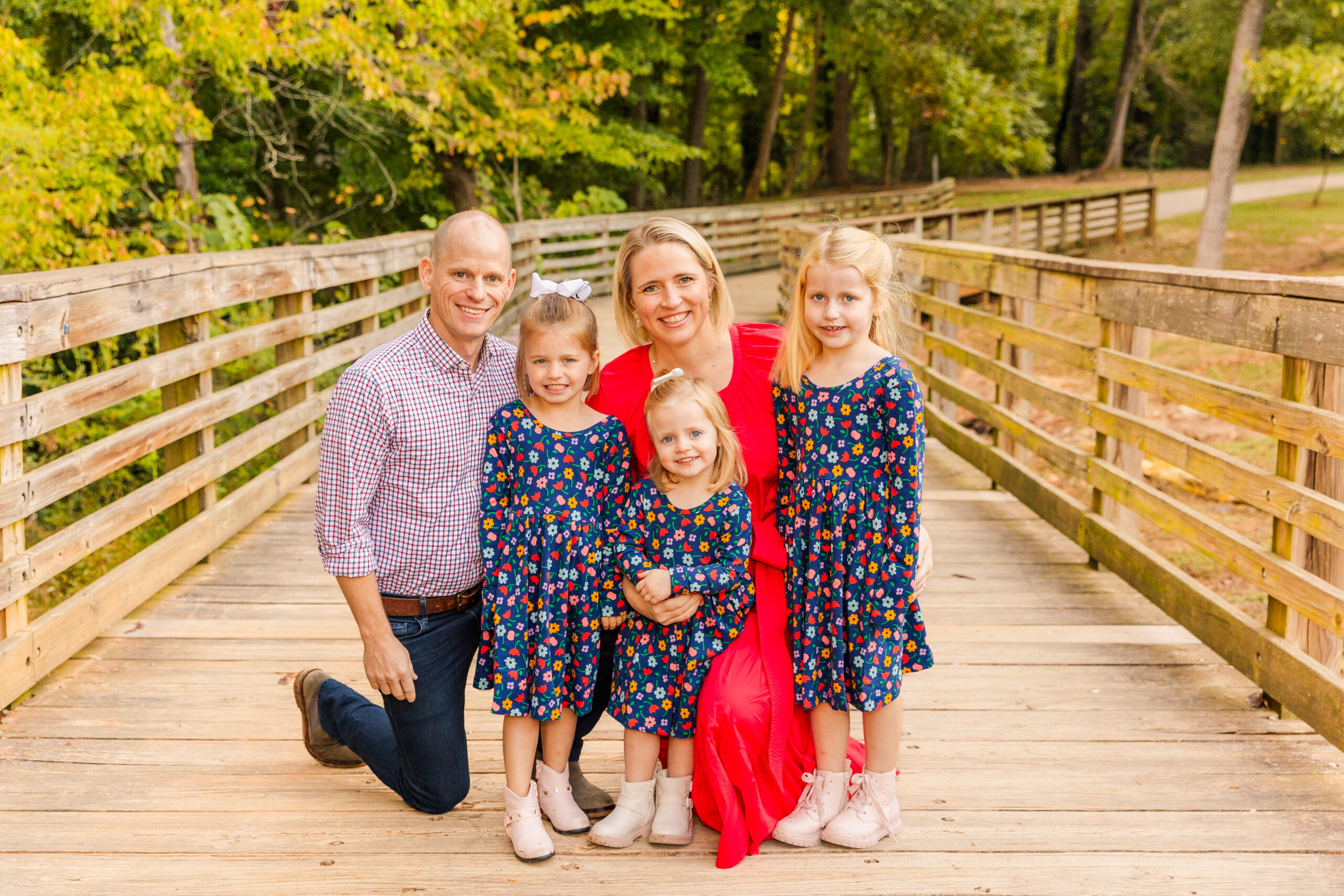 Parents with 3 young and toddler daughters standing on a bridge in a Brookhaven Atlanta park