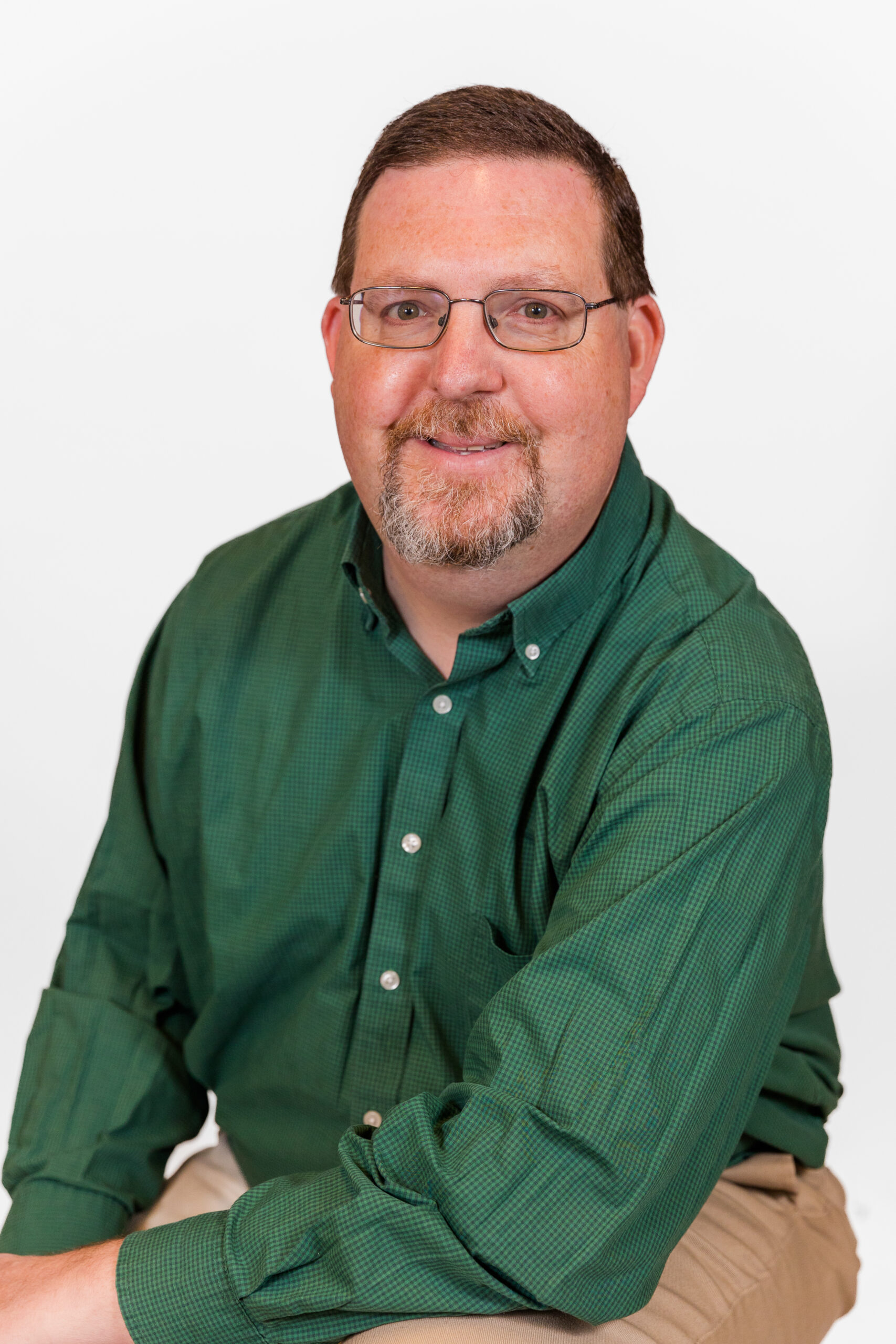 Man James Peavy wearing green shirt and beige pants sitting during headshots mini session in his Atlanta office