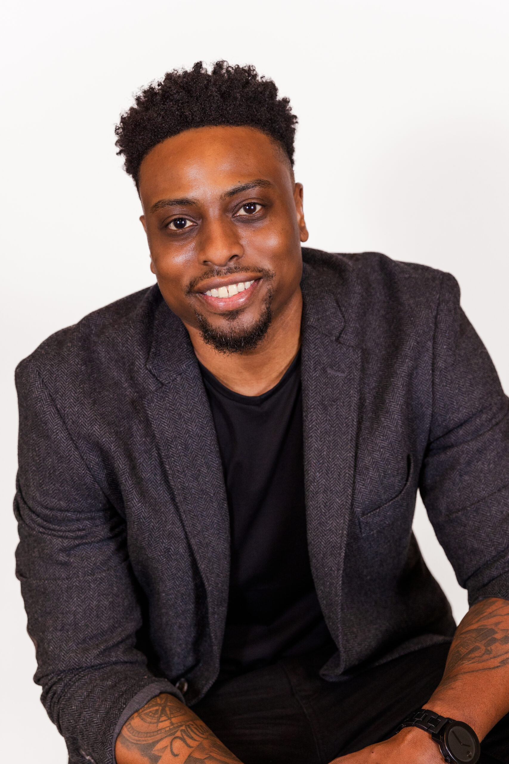 Mark Jordan sitting wearing a black tee-shirt and grey jacket during professional headshot mini session in the Atlanta midtown office