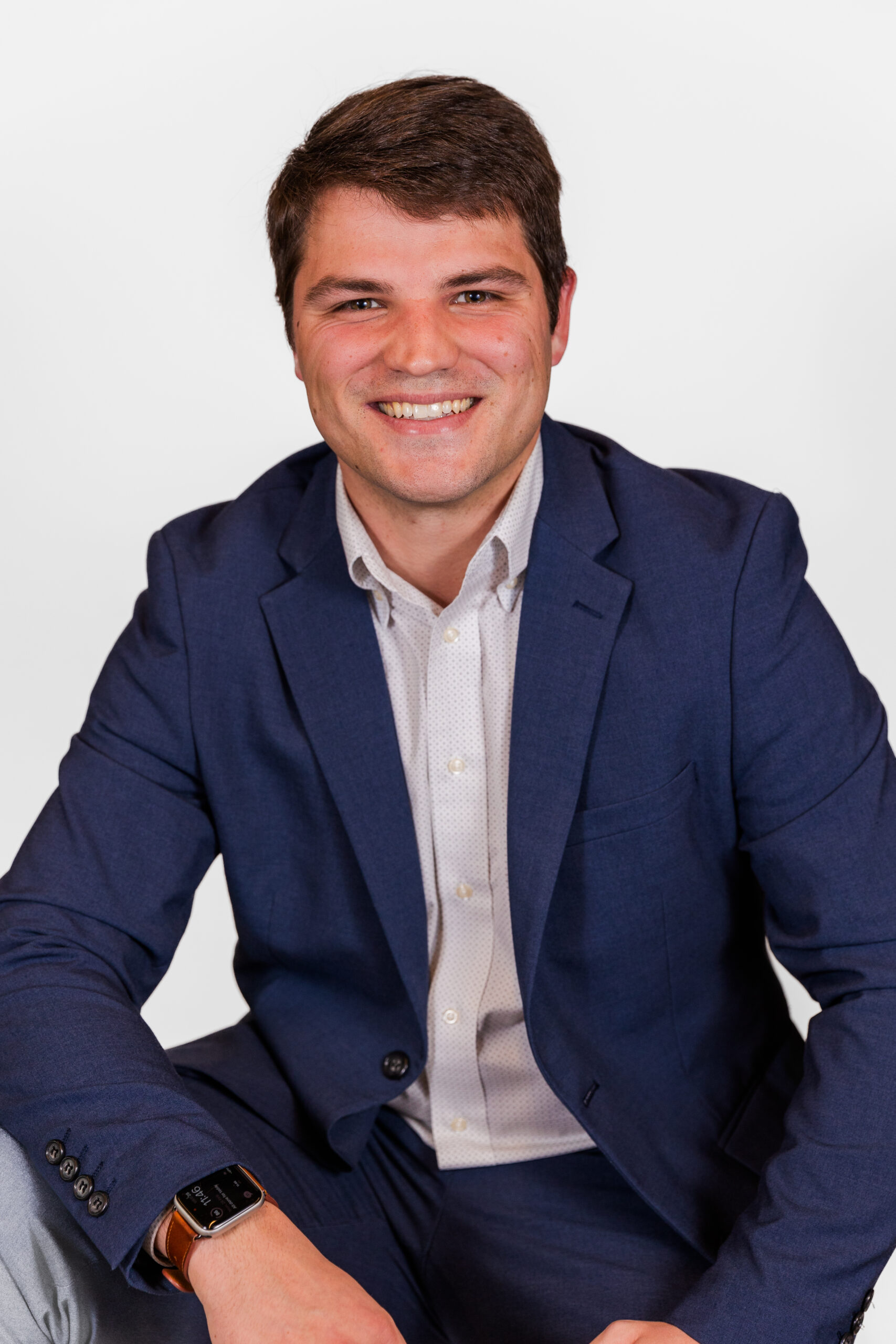 Robert Rowlinson wearing corporate outfit sitting in front of white backdrop during professional headshot photo session