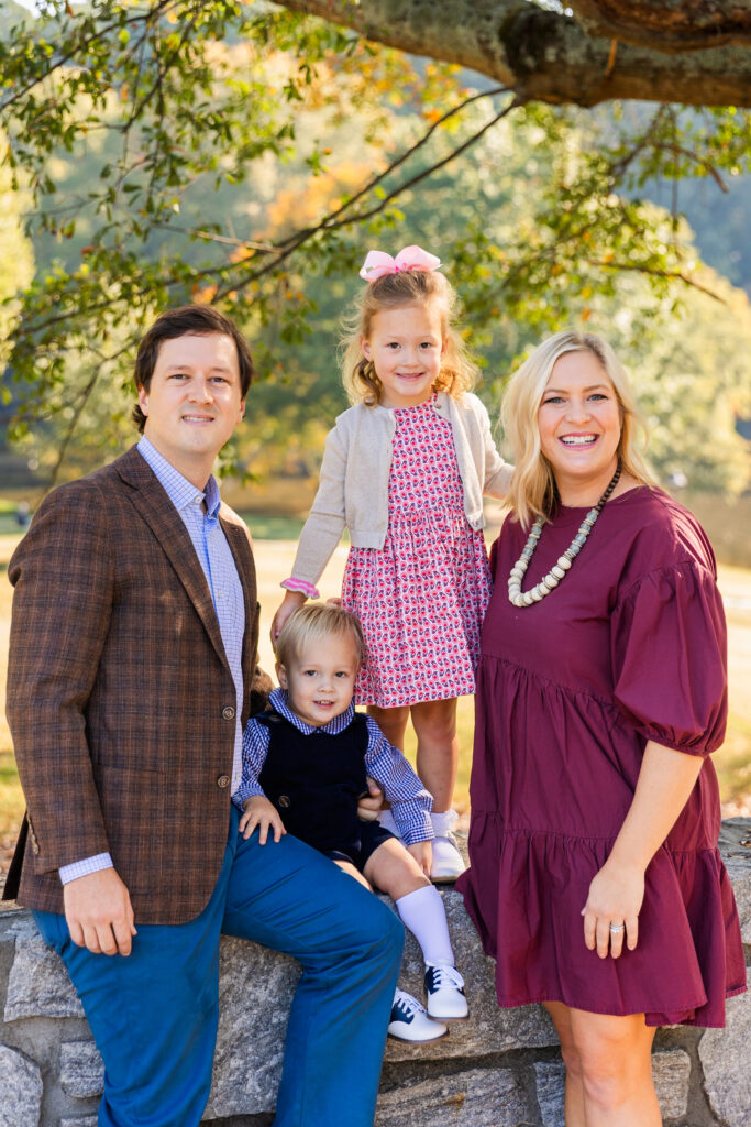 Parents with 2 toddlers sitting on a wall in a Buckhead park during family photo session with Atlanta photographer Laure Photography