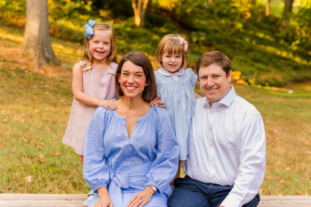 Family with toddlers wearing coordinated blue, white and light pink outfits during photoshoot in an Atlanta midtown park