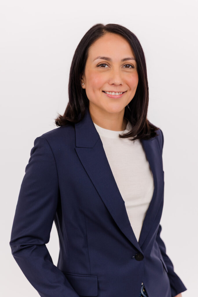 woman standing in front of white background wearing corporate outfit white tee-shirt and dark blue jacket during headshot photoshoot with Laure Photography