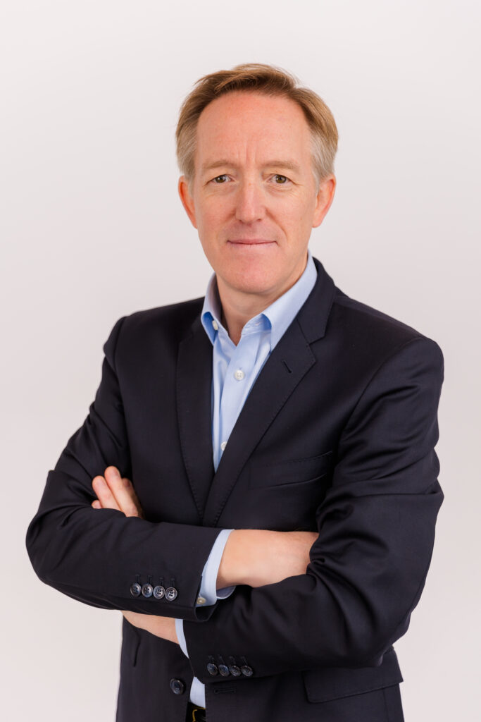 man standing arms crossed in front of white background wearing corporate outfit light blue shirt and dark jacket during headshot photoshoot with Laure Photography