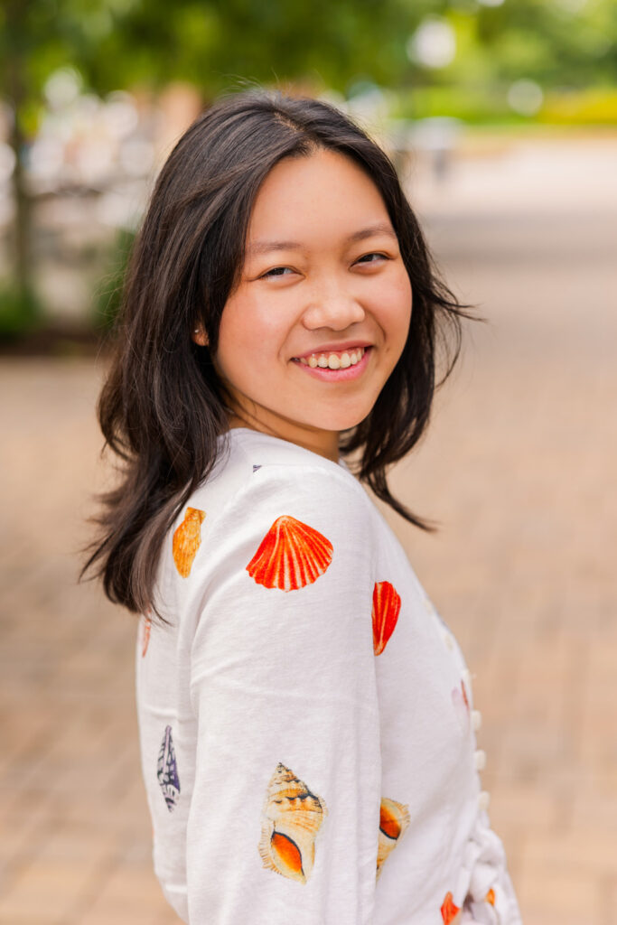 Senior girl standing, looking over her shoulder, wearing patterned shirt and shorts during Atlanta senior portraits with Laure Photography.