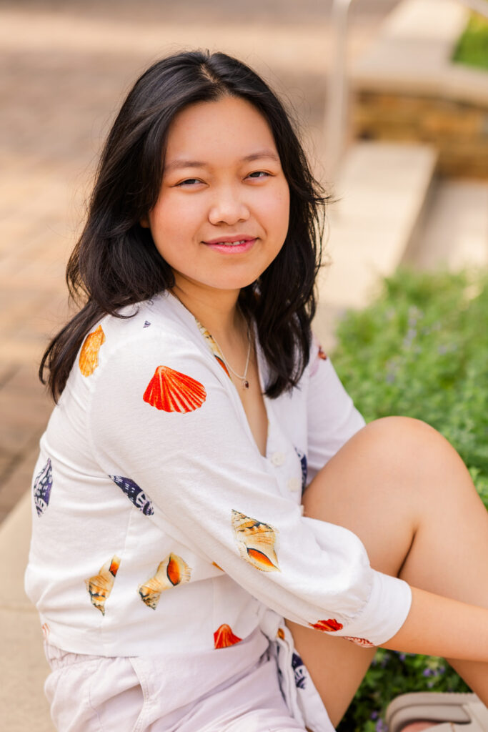 Senior girl sitting on the ground hugging one knee, looking sideways at the camera during her Atlanta senior session with Laure Photography.