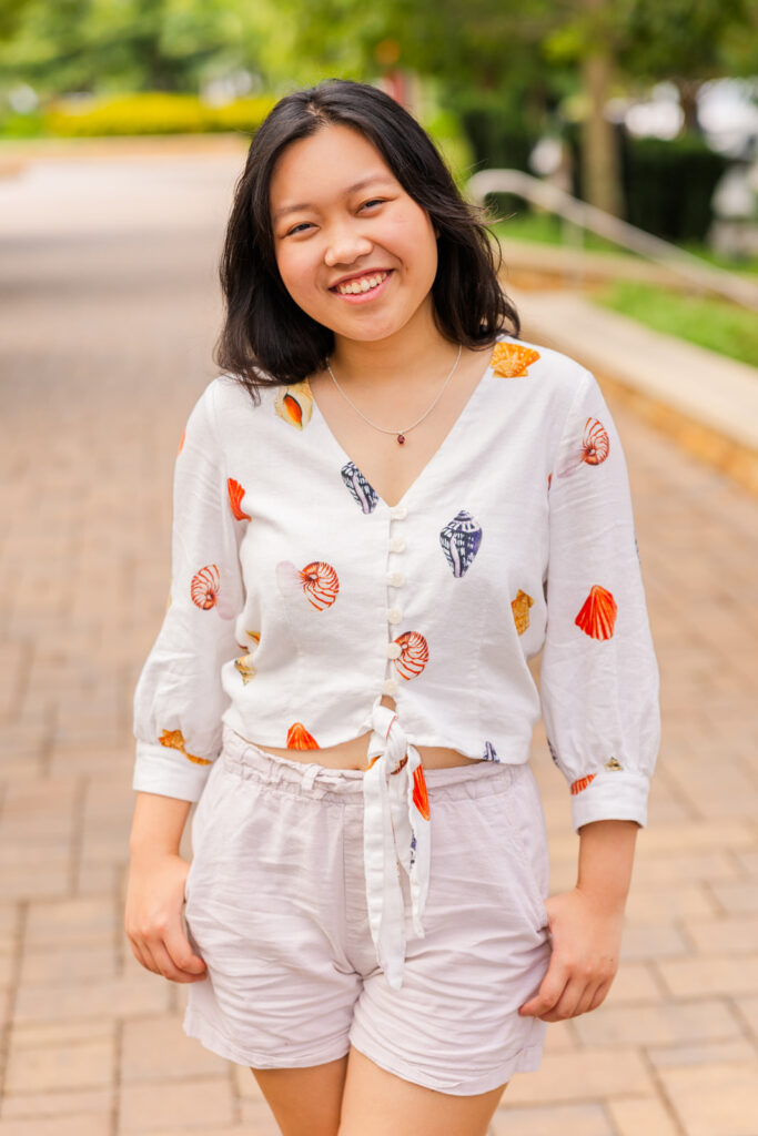Senior girl posing confidently on a street path, hands in pockets, during her Sandy Springs senior session with Laure Photography.