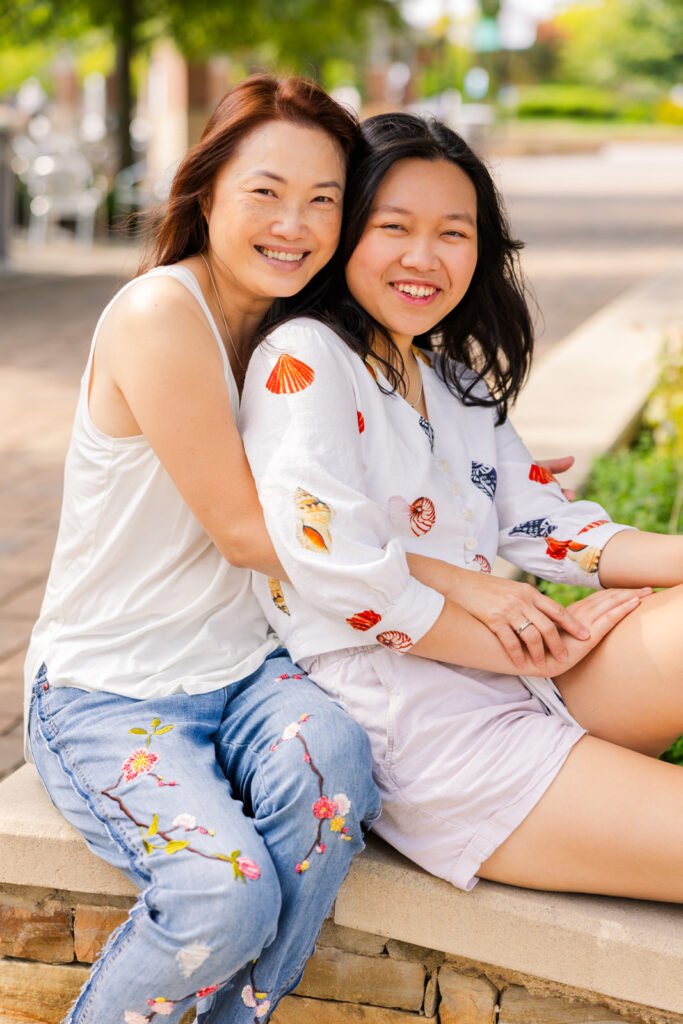 Senior girl and her mom sharing a sweet hug outdoors with city vibes during a high school senior photoshoot with Laure Photography in Sandy Springs.