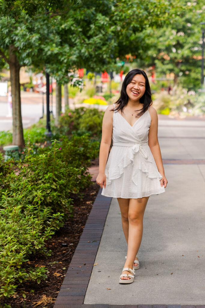 Senior girl laughing while walking toward the camera during her joyful Sandy Springs senior session with Laure Photography.