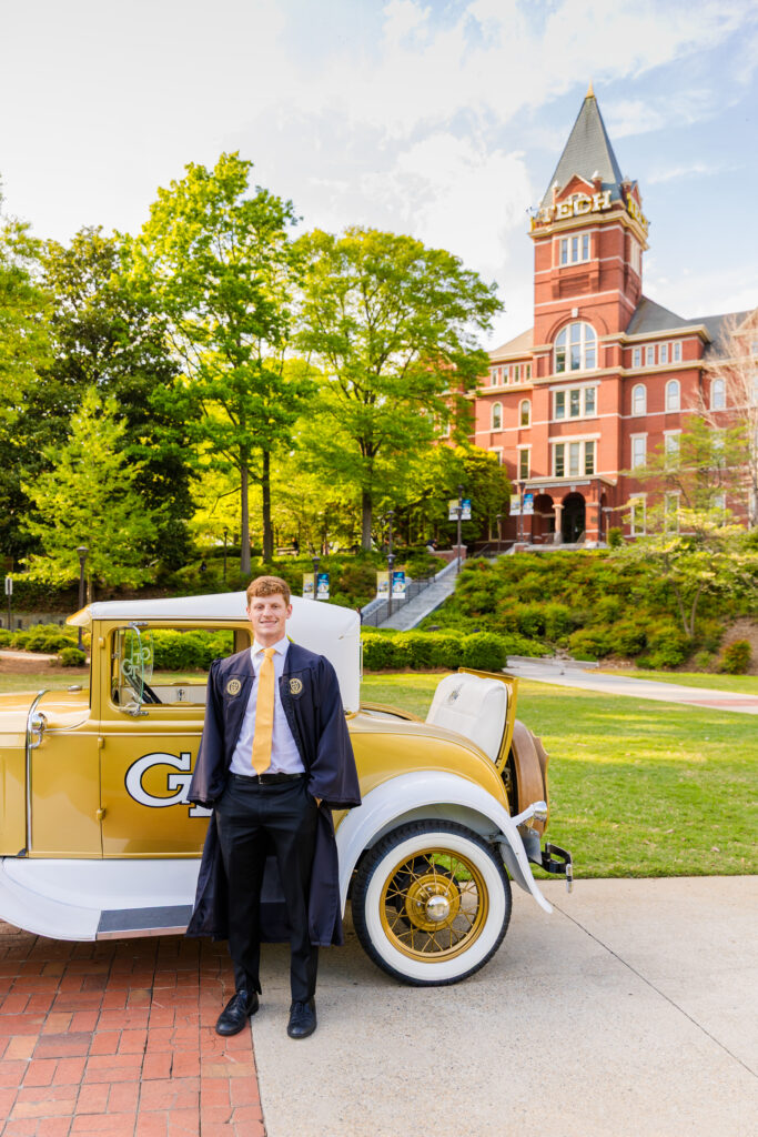 Jason in senior graduation outfit standing by the Ramblin' Wreck with Georgia Tech Tower in the background.