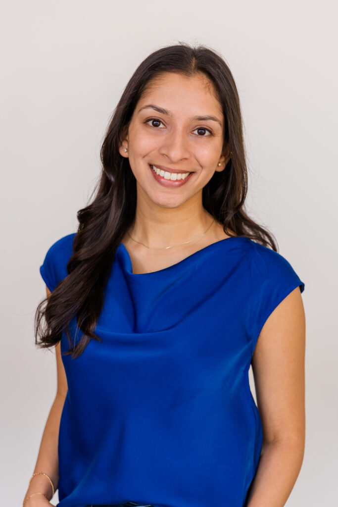 Woman in a blue top smiling in front of a white backdrop during a formal studio headshot session in Atlanta by Laure Photography
