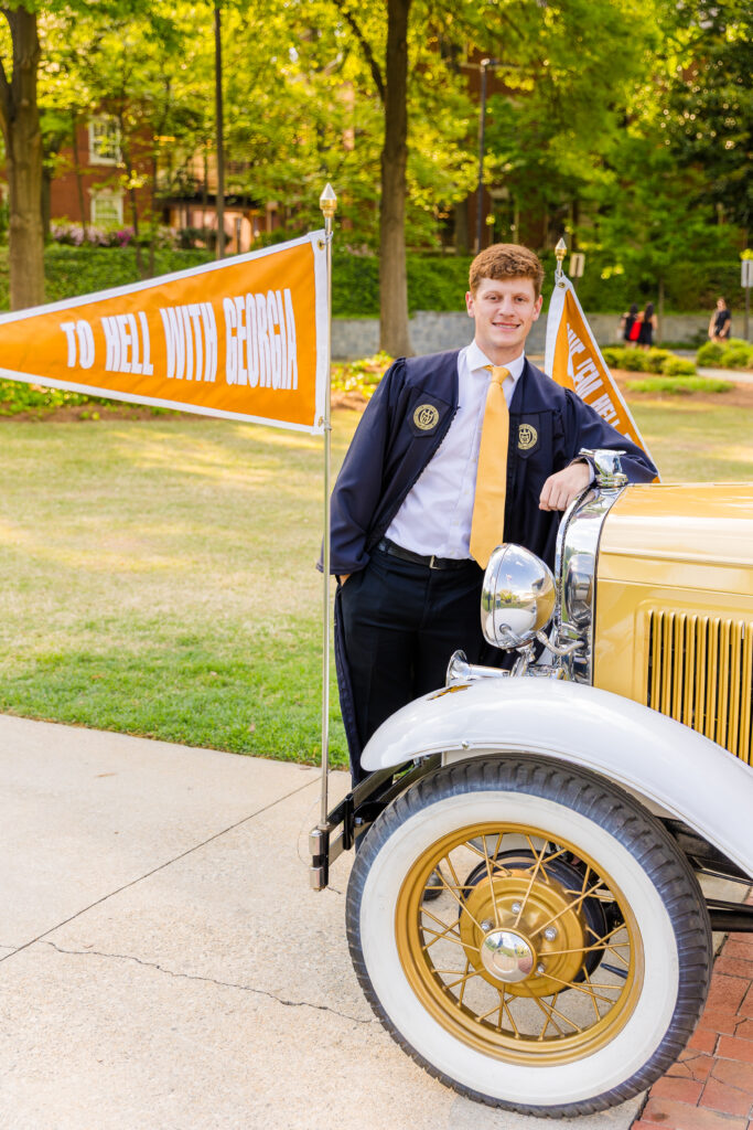 Jason standing proudly in front of the Ramblin' Wreck with the "To Hell With Georgia" banner.