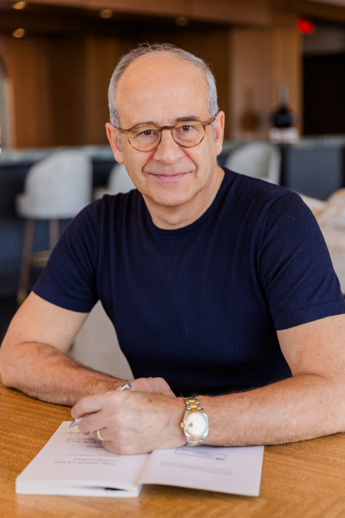 Ahmet Bozer wearing a black t-shirt, signing a book at a restaurant table during his Atlanta Buckhead personal brand photo session