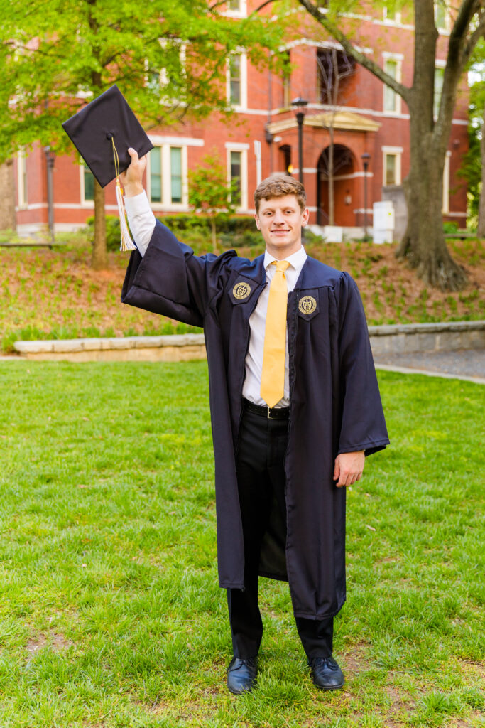 Jason holding his graduation hat high in celebration on Georgia Tech campus.