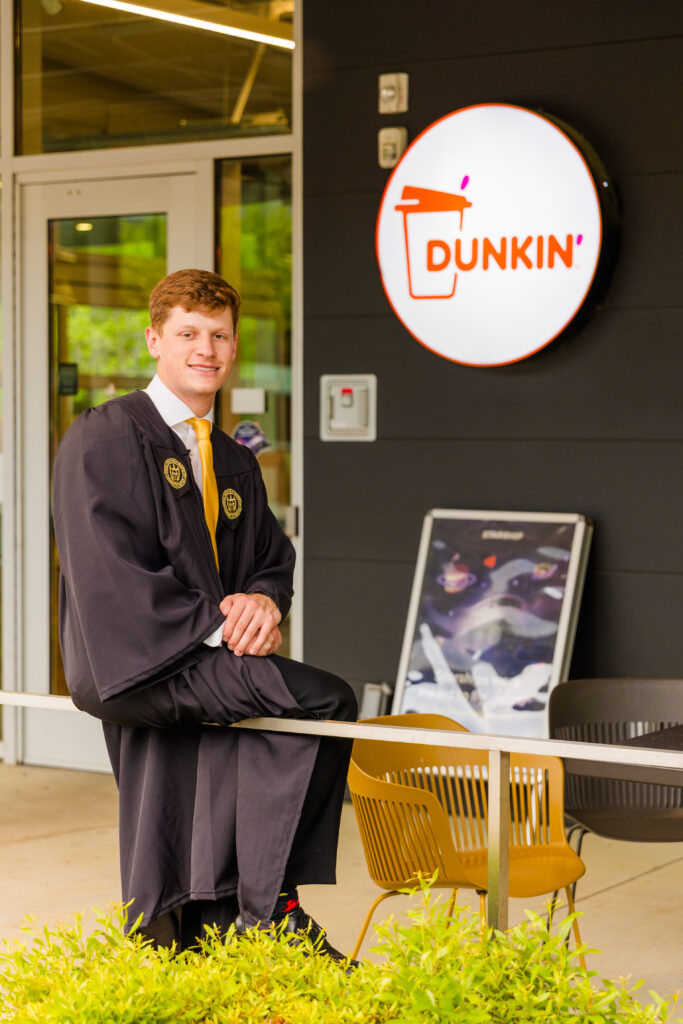 Jason sitting in front of Dunkin’, a personal favorite spot from his student life.