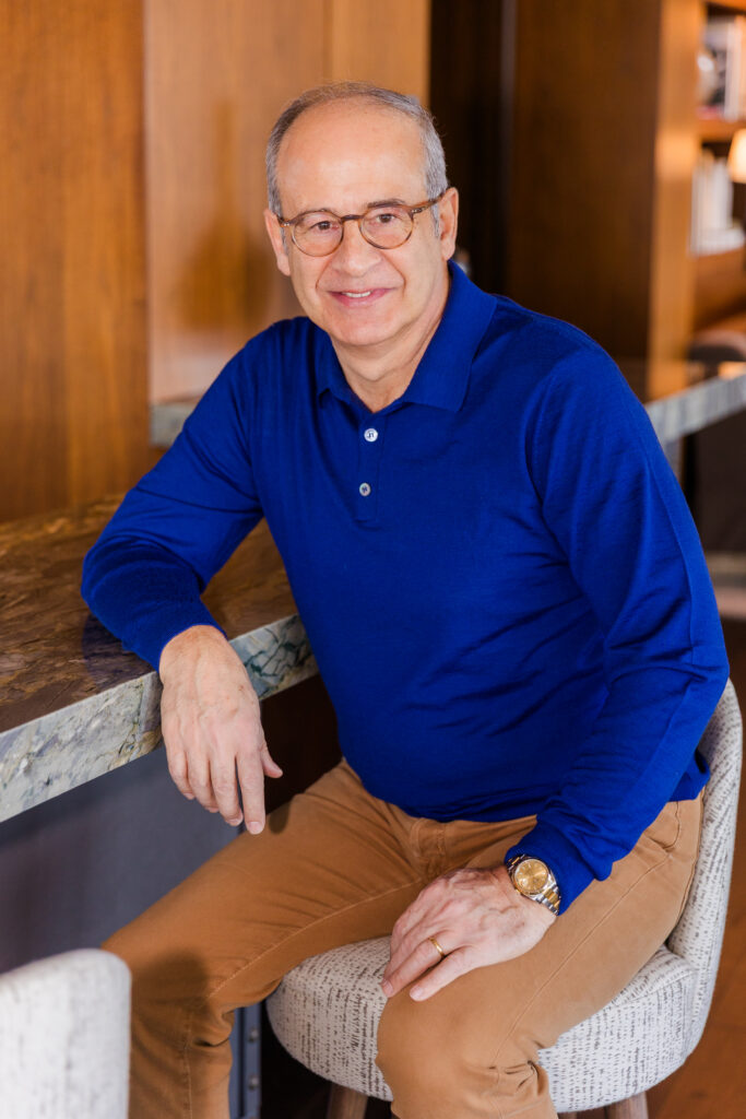 Ahmet Bozer wearing a casual outfit, sitting on a bar stool with hand resting on the countertop during his Atlanta Buckhead session