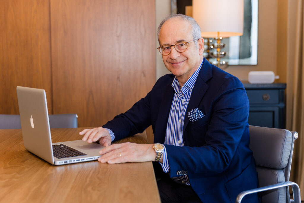 Ahmet Bozer wearing a formal outfit sitting at a desk, working on his computer, smiling at the camera during his Atlanta Buckhead branding session