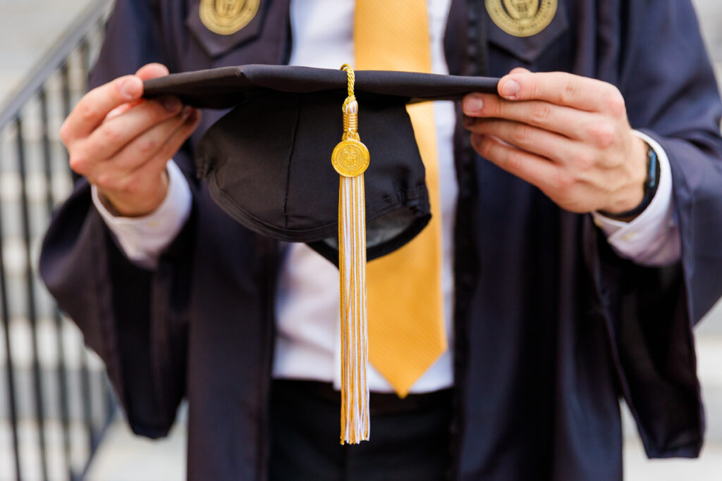 Detail shot of Jason holding his graduation cap in both hands.