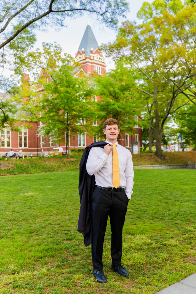 Jason standing proudly in front of the Georgia Tech Tower, holding his graduation gown over his shoulder.