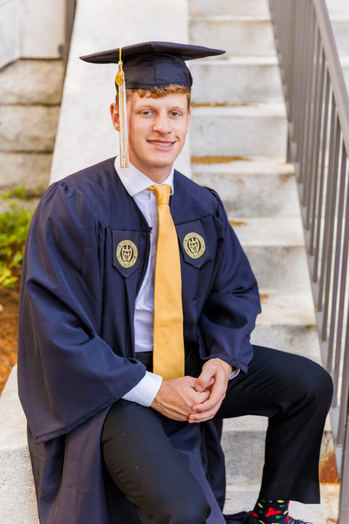 Jason sitting on campus stairs in his Georgia Tech graduation attire.