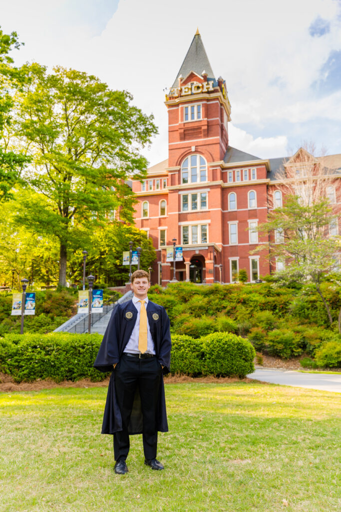Wide shot of Jason standing on the campus lawn in front of the Georgia Tech Tower.