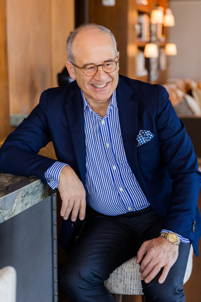 Ahmet Bozer wearing a formal outfit, sitting on a bar stool, talking and laughing with someone off camera during his Atlanta branding session