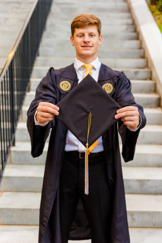 Graduation cap in sharp focus with Jason standing blurred in the background.
