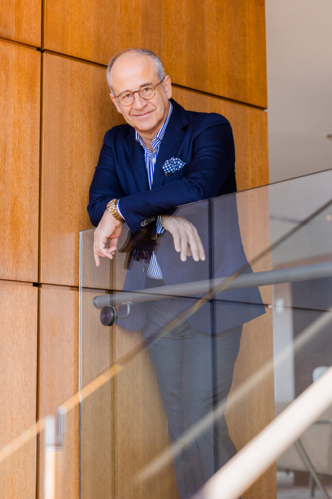 Ahmet Bozer resting his arms on a transparent staircase ledge, photographed from below during his personal brand photo session in Atlanta Buckhead