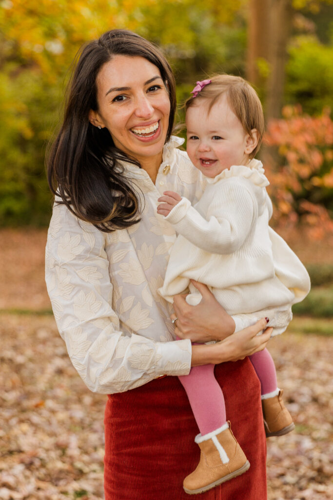 Mom holding and hugging her baby daughter while standing in a sunlit Atlanta park during a family photo session by Laure Photography.