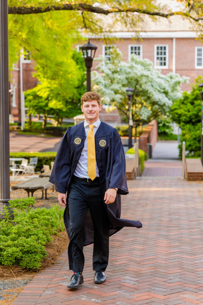 Jason walking around Georgia Tech campus in graduation gown and yellow tie.