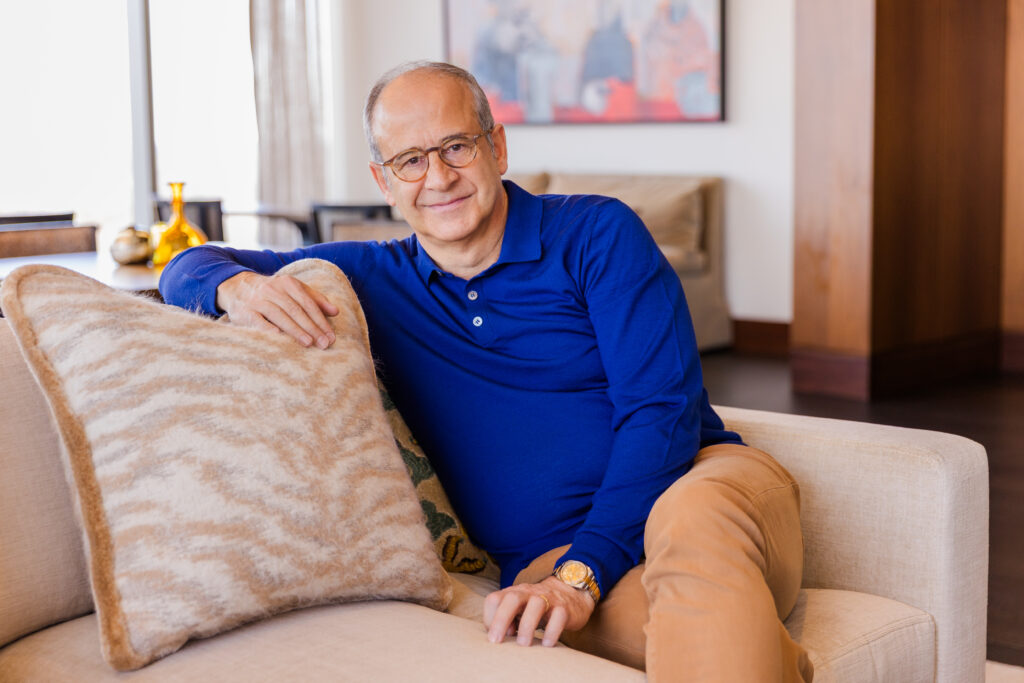 Ahmet Bozer wearing a blue top and beige pants sitting on a modern sofa during a personal brand photo session in Atlanta Buckhead by Laure Photography
