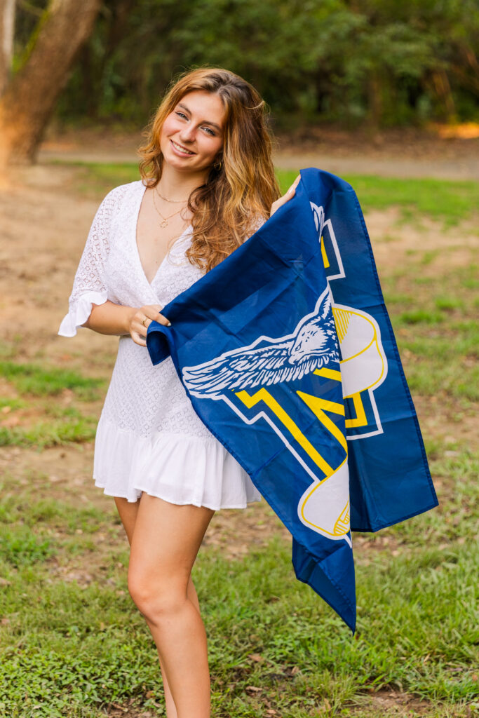 Sienna proudly holding her Marist High School banner during her senior session in a sunny Atlanta park