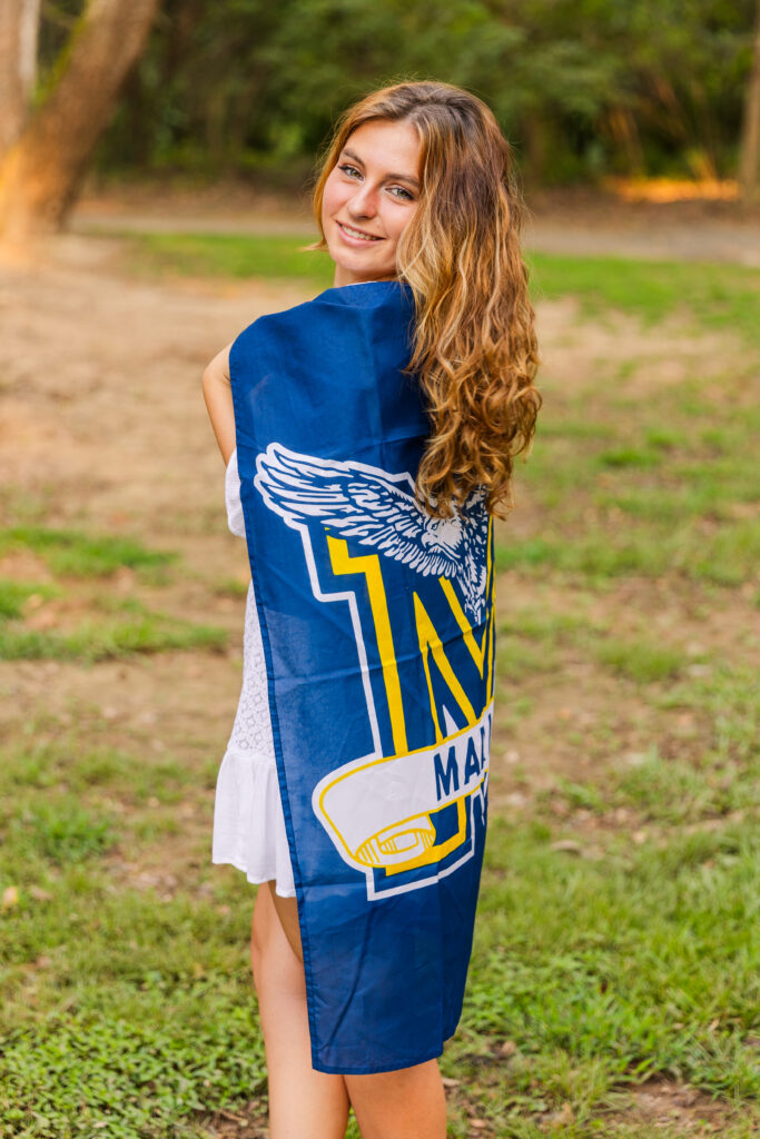 Senior girl wrapped in her Marist High School banner smiling in the middle of a green Atlanta park