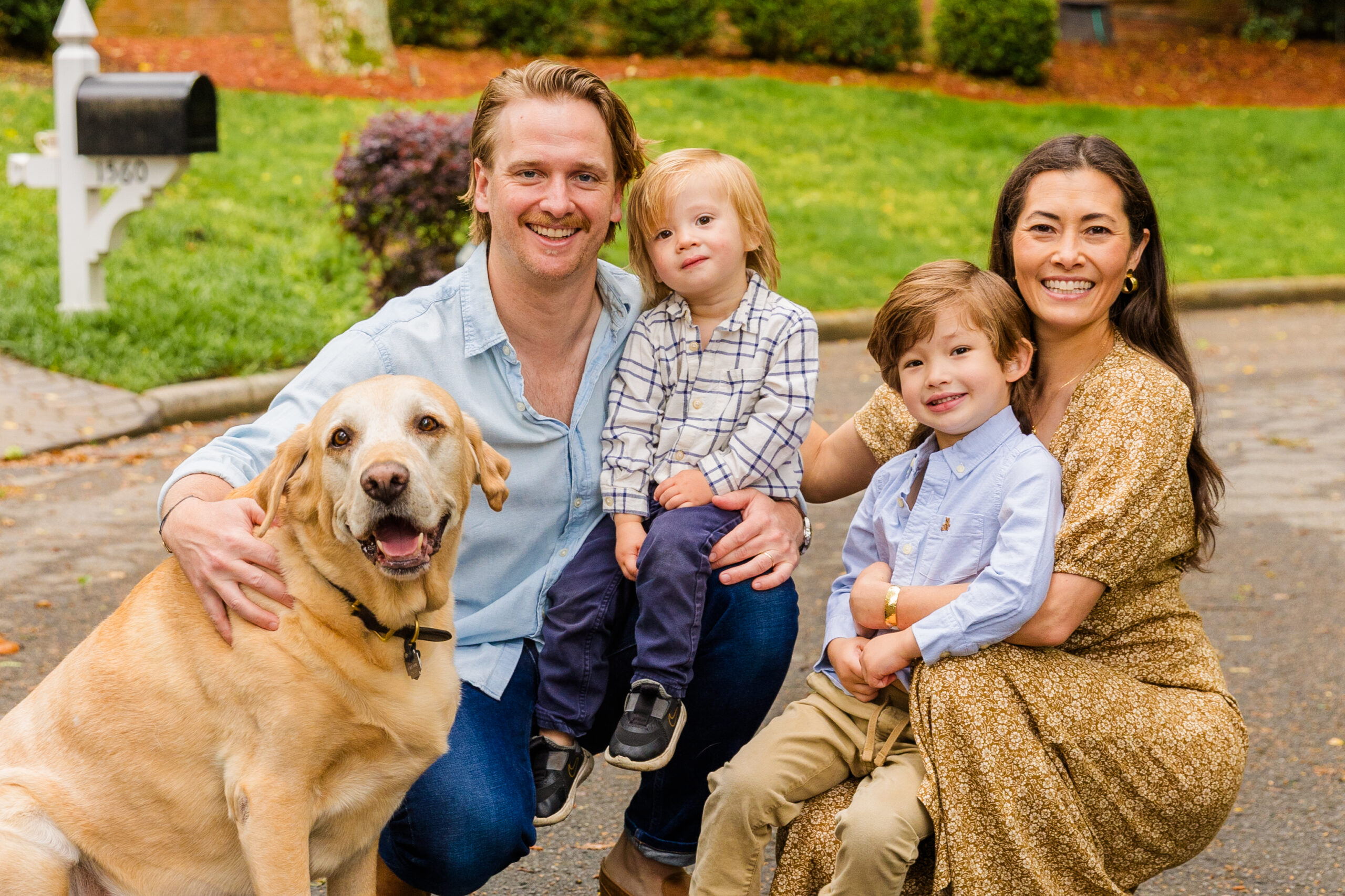 Parents squatting in front of house wearing coordinated outfits engaging with their children during an Atlanta family photo session.