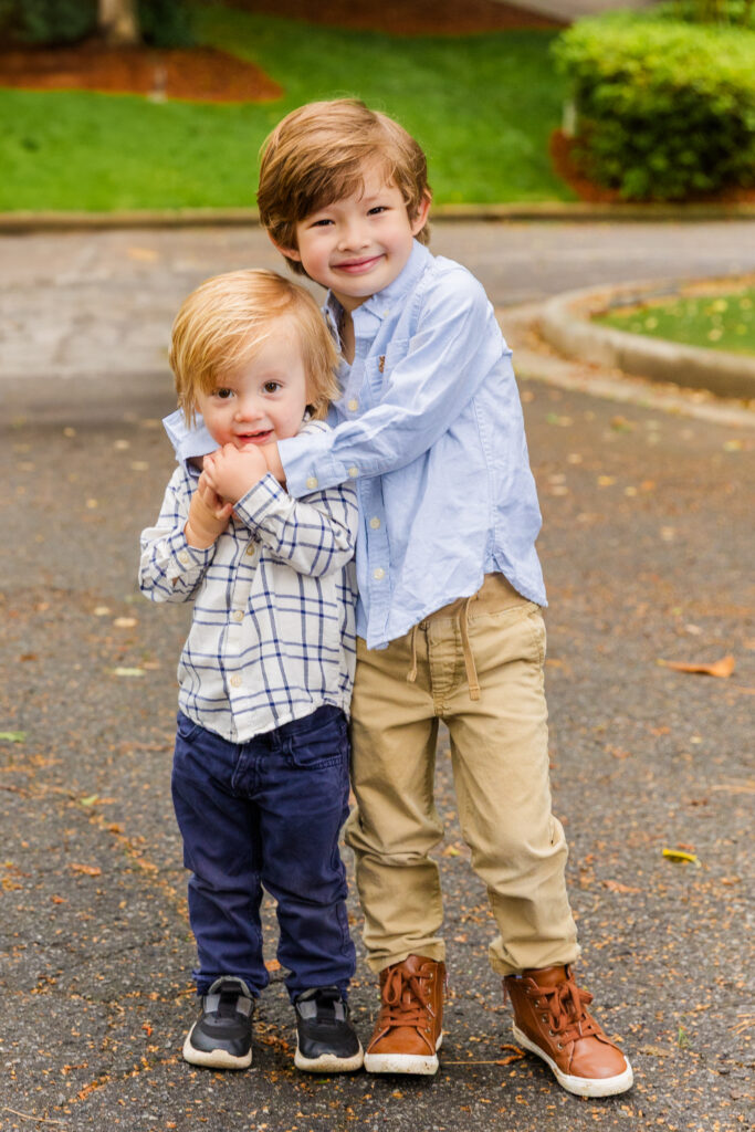 Sibling hug moment with matching blue and beige outfits.