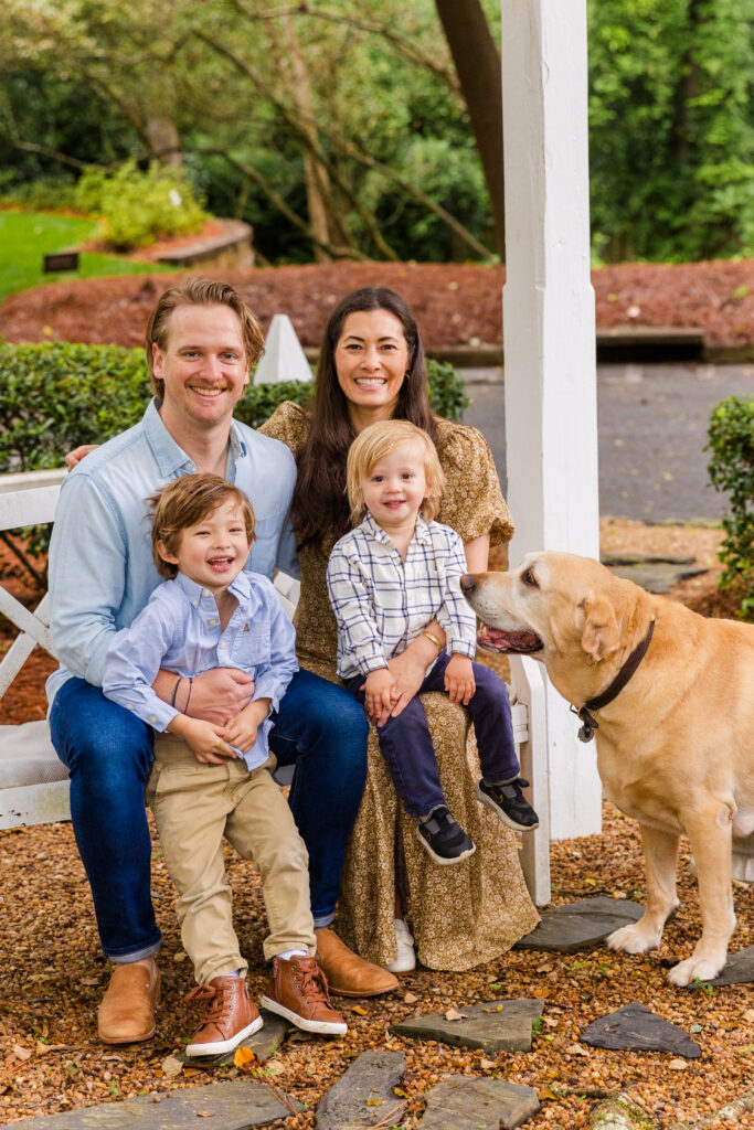 Family sitting on a white bench with their dog, sharing a joyful moment.