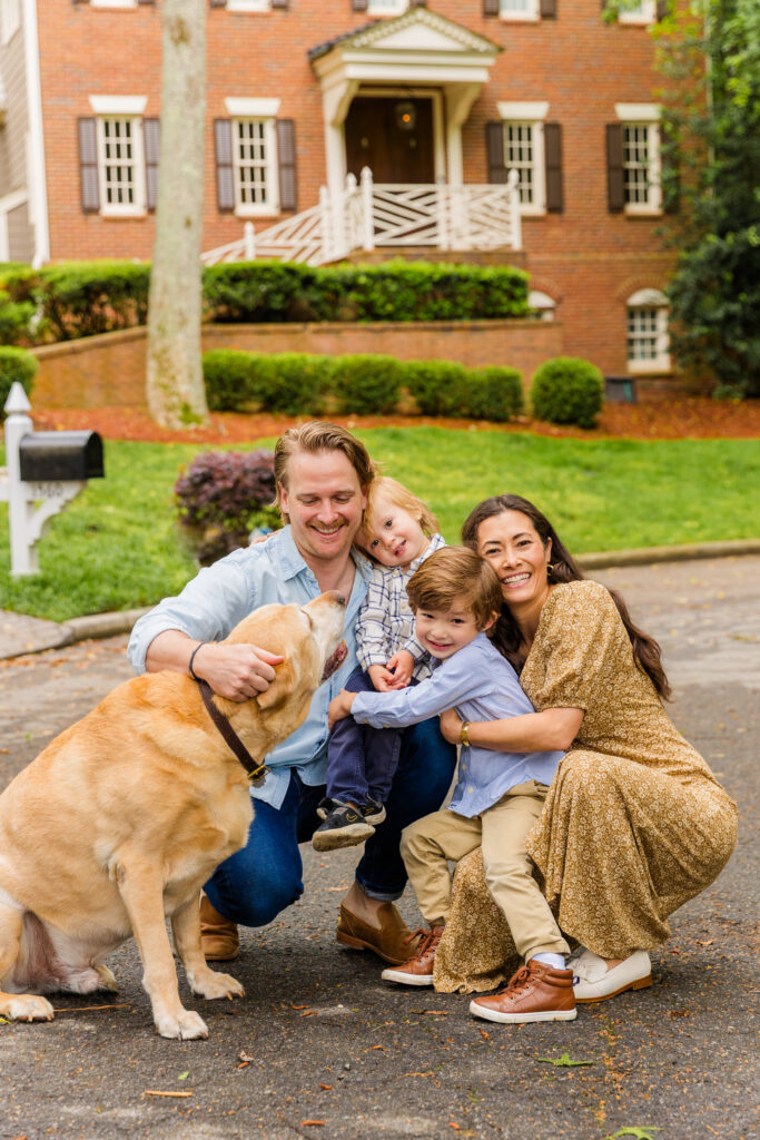 Family hugging with their dog in front of their Atlanta home.