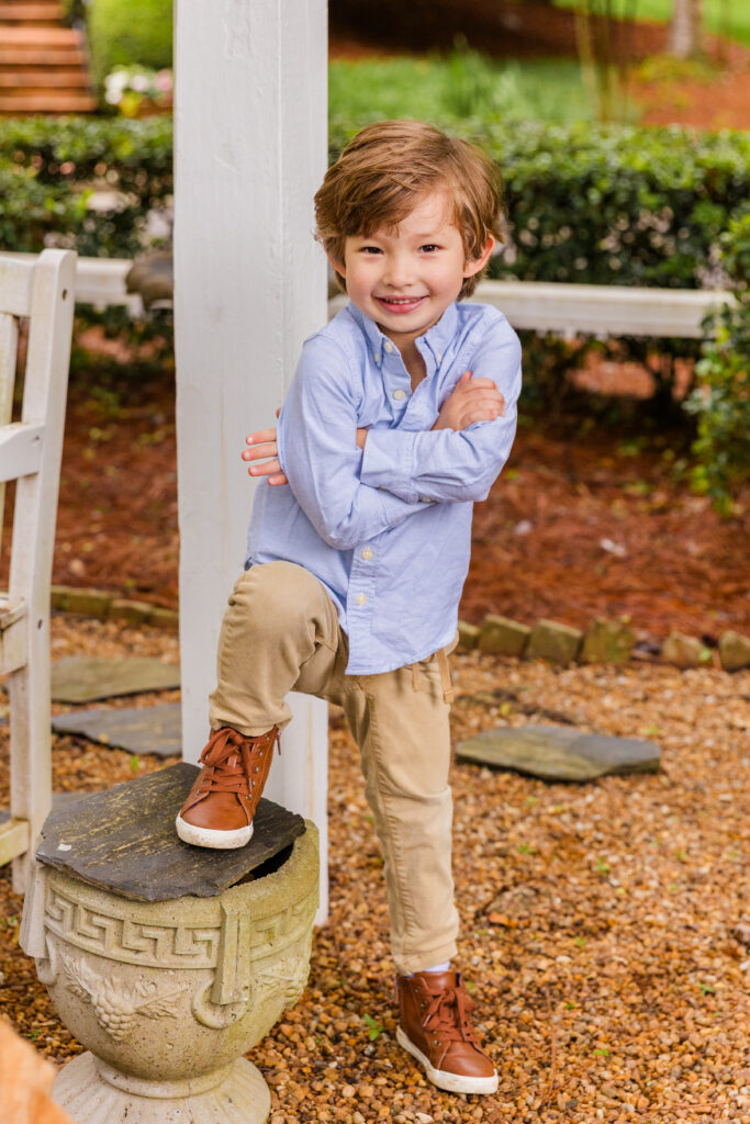 Young boy standing with arms crossed, mimicking a teenager’s pose.