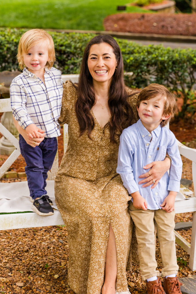 Mother and two sons in a sweet portrait pose on a white bench.